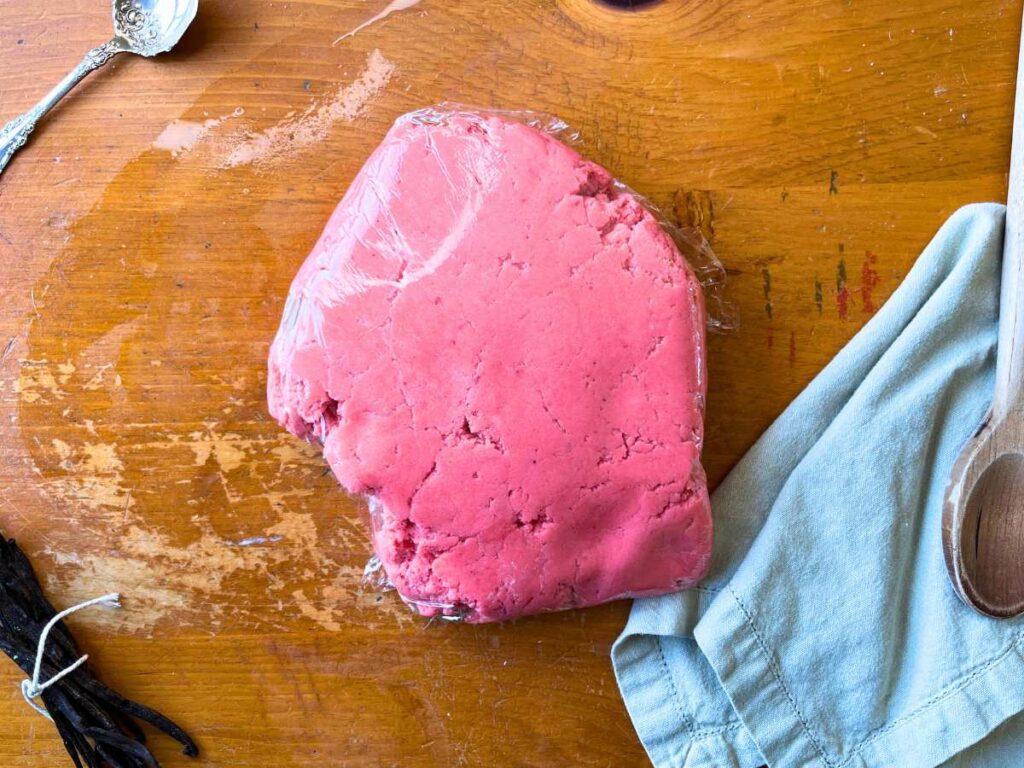 Pink cookie dough wrapped in plastic wrap.