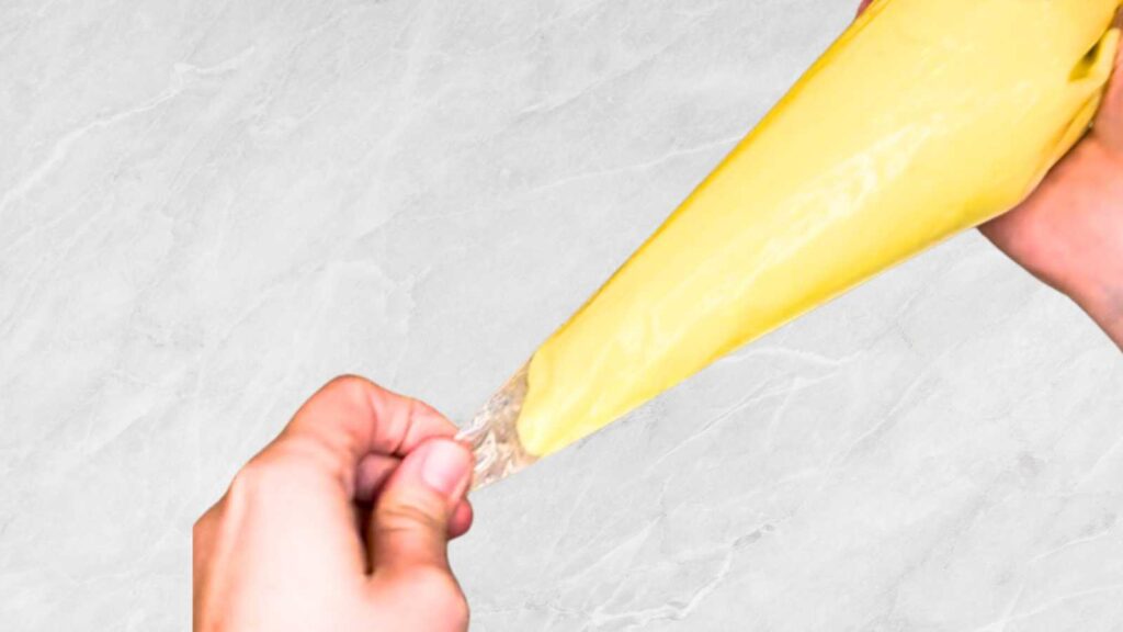 A woman is holding a piping bag full of vanilla pastry cream.