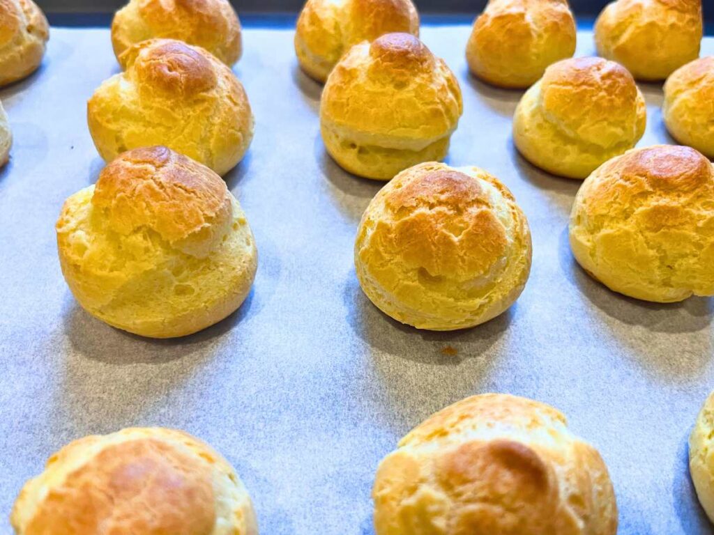 A tray with baked profiteroles on it.