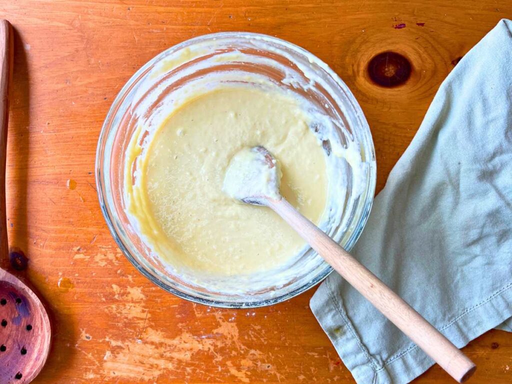 A glass bowl with spaetzle batter inside.