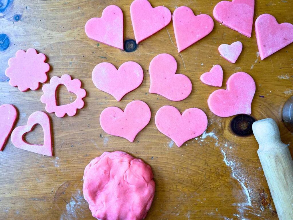 Pink cookie dough cut outs in the shape of hearts.