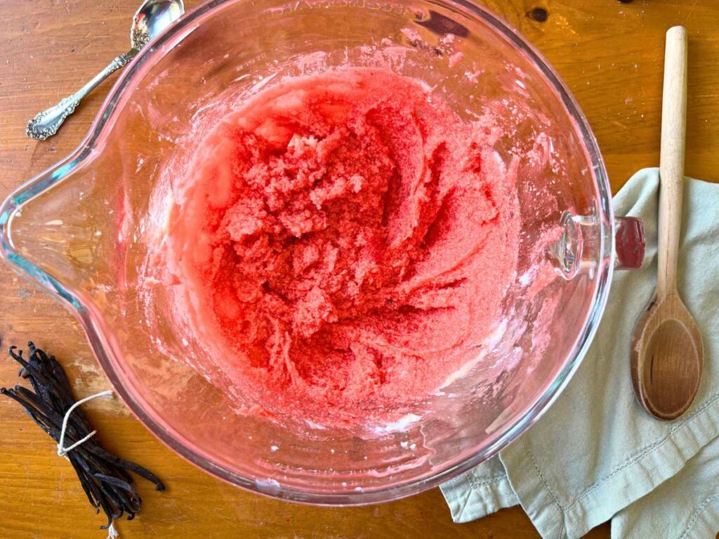 A glass bowl with pink batter inside.