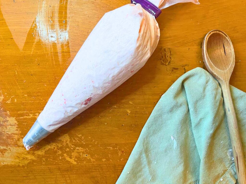 A piping bag with strawberry icing inside.