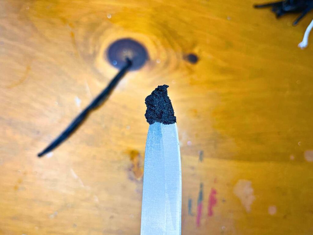 A woman showing vanilla bean seeds in the tip of a knife.