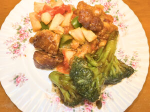 A plate of Chinese food. There is broccoli and a stir fried pork and veggie dish on the plate.