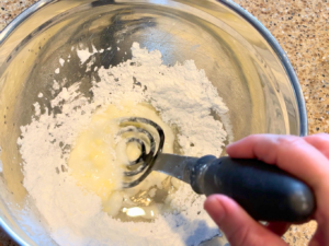 Woman mixing icing sugar, water, butter, and vanilla into a glaze.