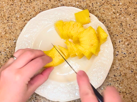 A woman chopping pineapple.