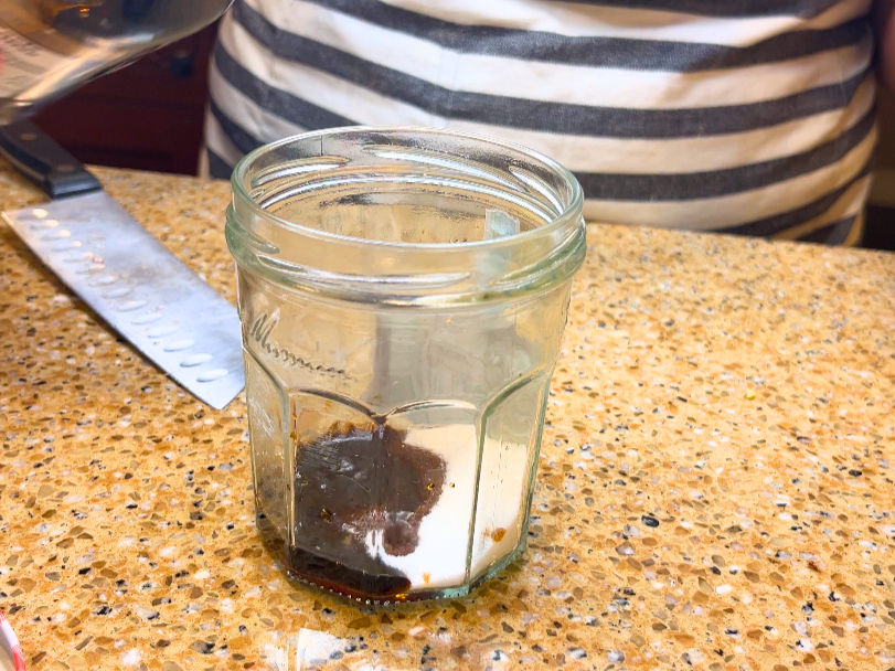 A glass jar with sugar and tamari sauce in it.