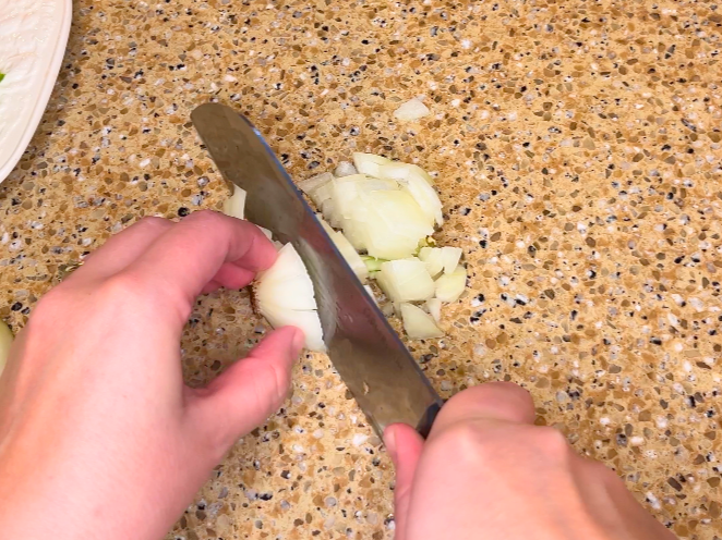A woman chopping an onion.