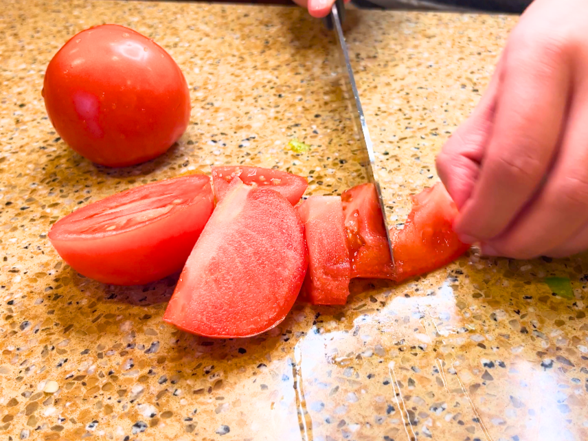 A woman chopping a tomato.