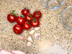 Tomatoes and cloves of garlic on a counter.