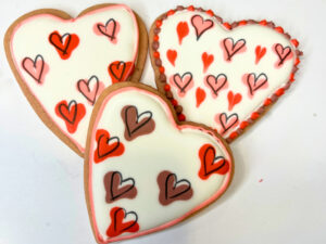 Pink heart cookies decorated with royal icing in little heart design.