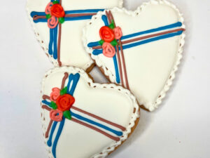 Three heart sugar cookies decorated as white chocolate boxes.