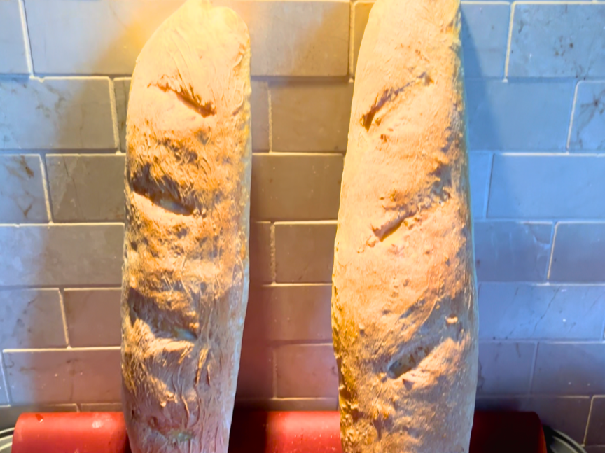 Two baguettes cooling against a wall.