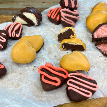 An assortment of chocolates on a piece of parchment paper on a wooden table.