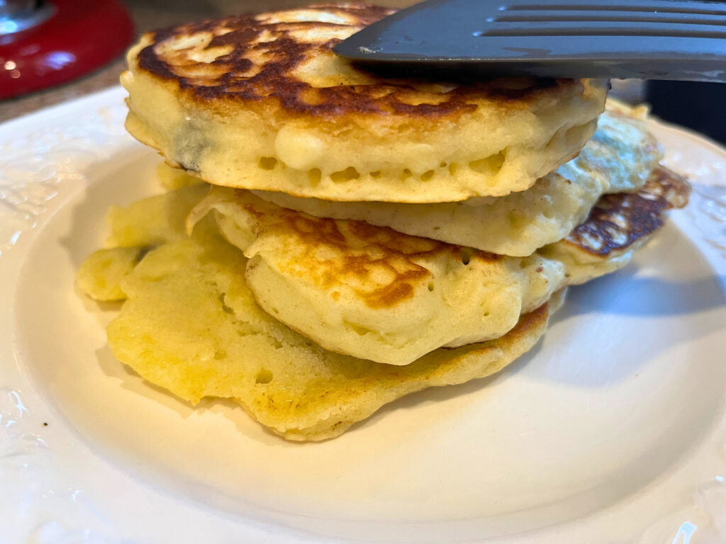A stack of cooked pancakes on a white plate.