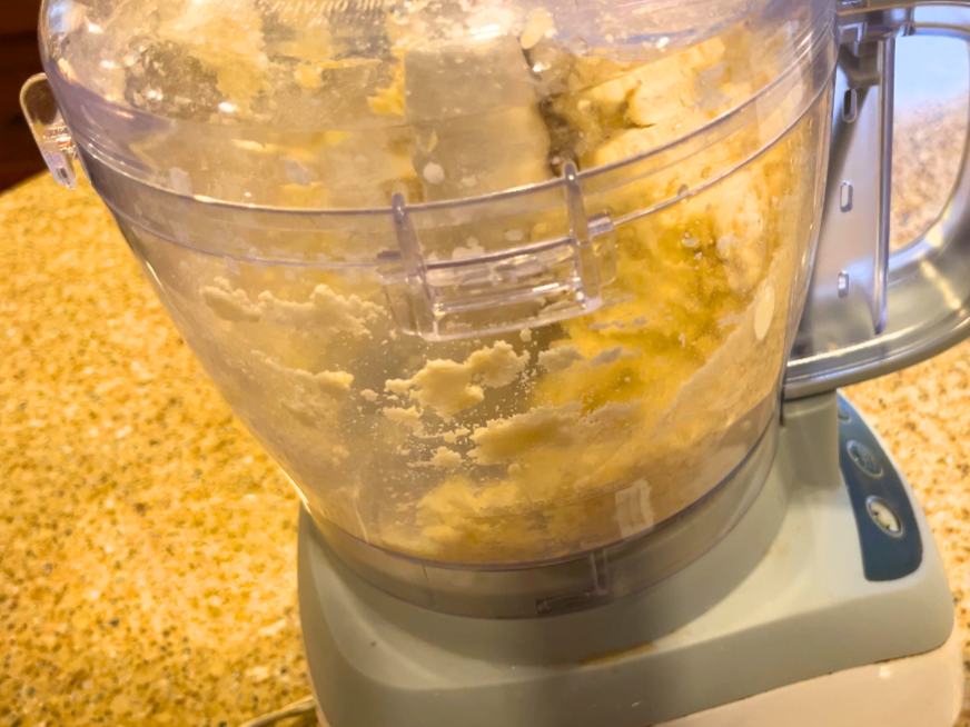 A food processor with pie crust dough in it.