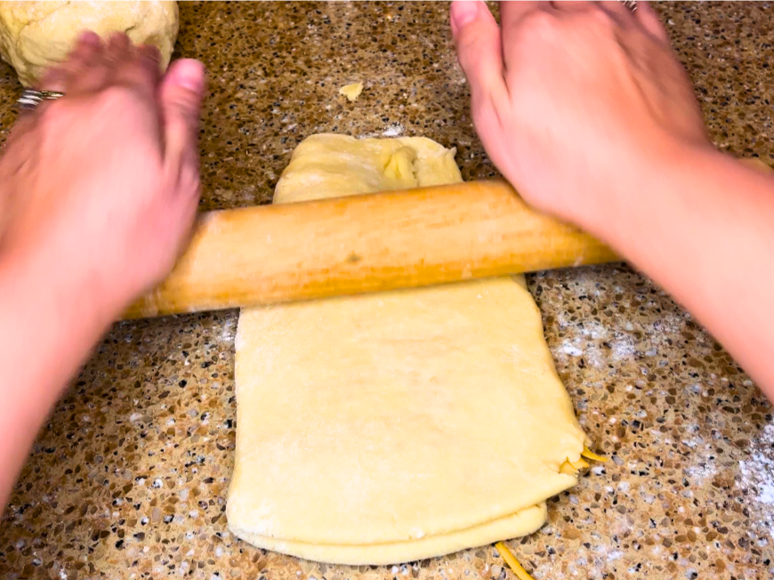Woman rolling dough out with a rolling pin.