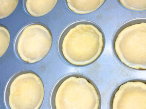 A muffin tin filled with pie dough.
