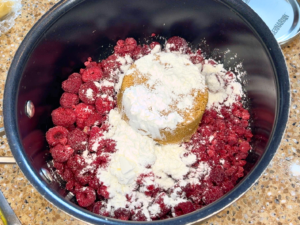 A sauce pot with raspberries, cornstarch, and brown sugar.