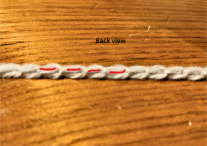 A crochet chain, in grey yarn, turned to show the back of the chain.