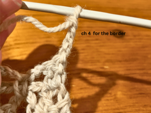 Woman crocheting grey yarn with a crochet hook.