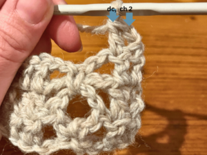 Woman holding grey yarn and a crochet hook.