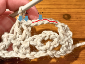 Woman holding grey yarn that she is using to crochet with a crochet hook