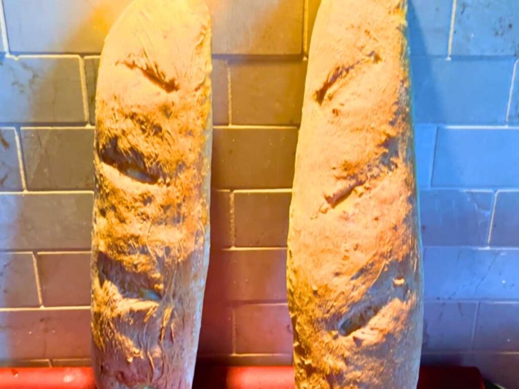 Two loaves of French bread leaning against the wall.