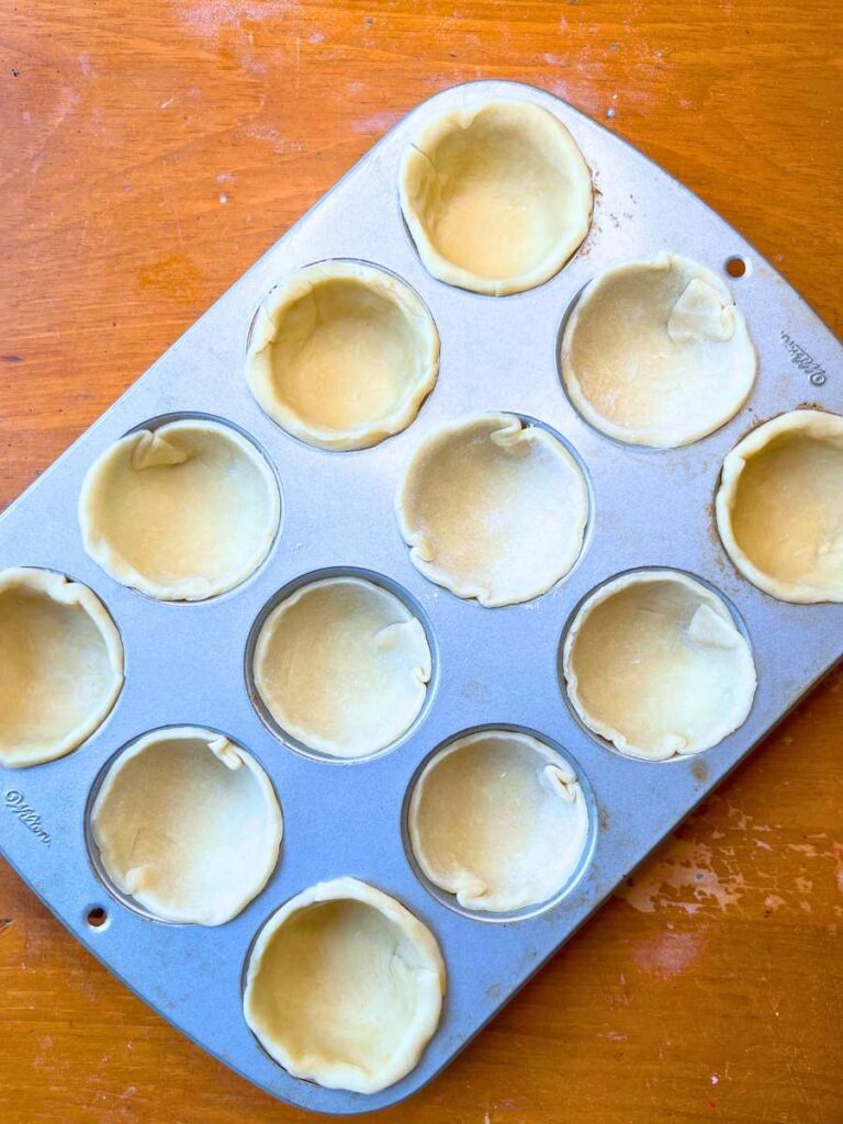 A muffin tin filled with pie dough.