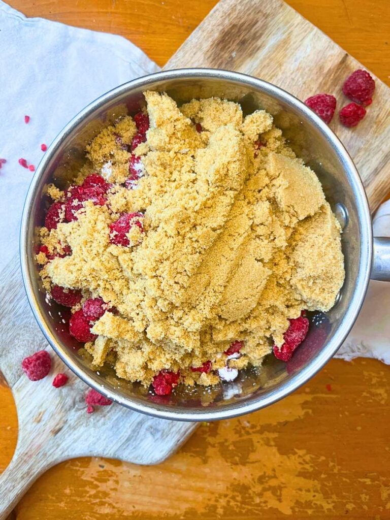 A metal sauce pot filled with raspberries, cornstarch, and brown sugar.