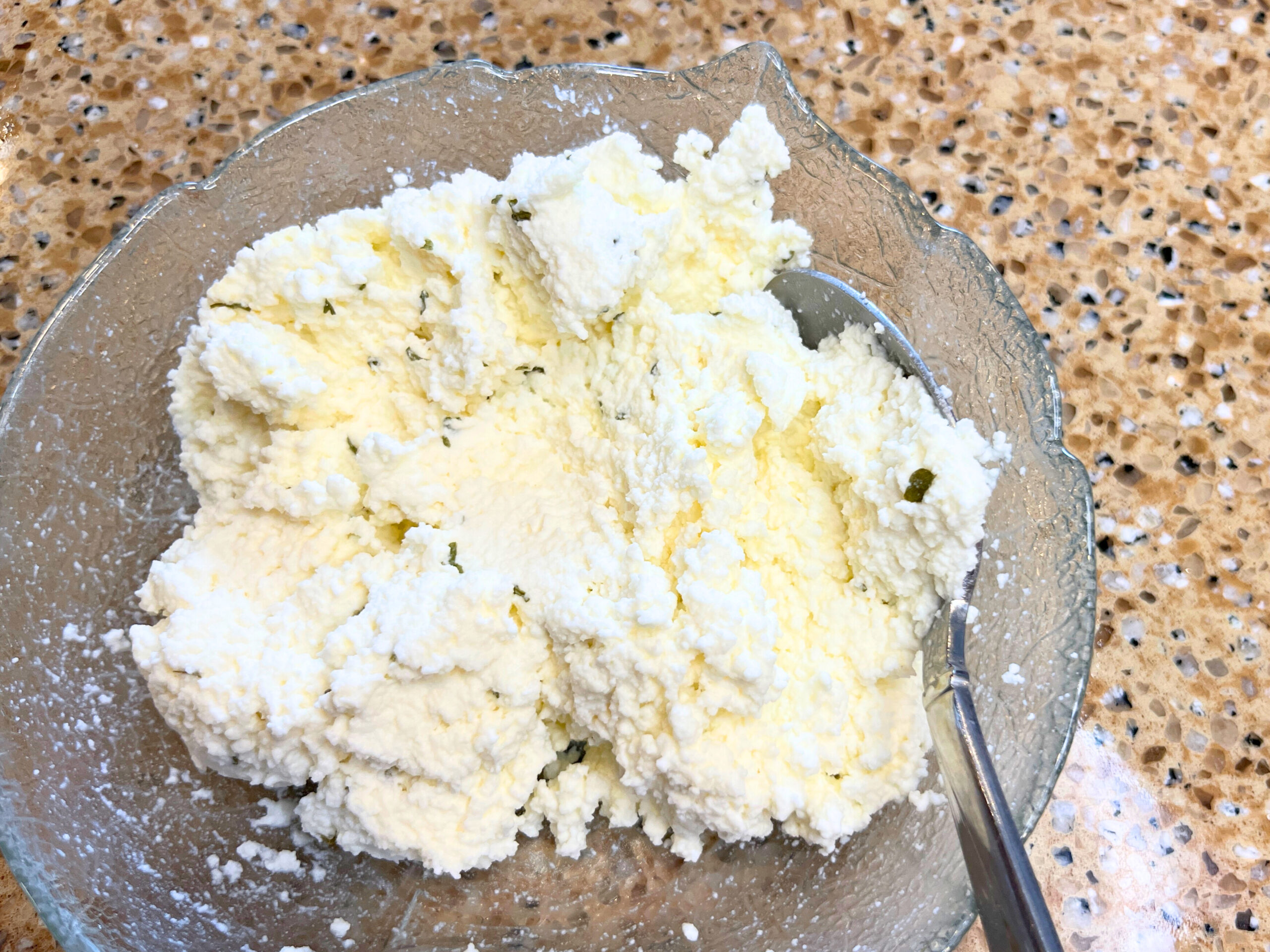 A glass bowl with ricotta cheese