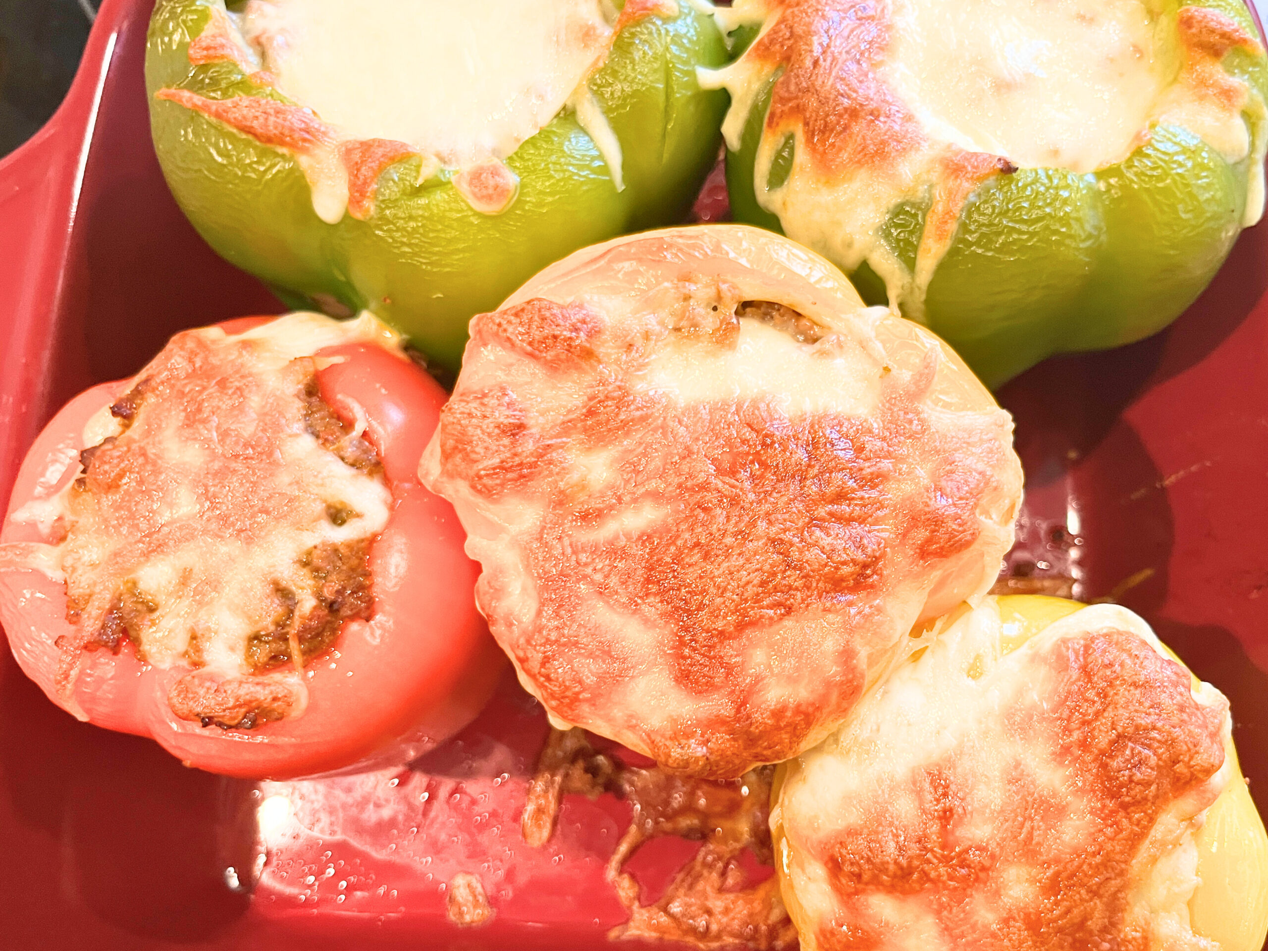 A casserole dish with cooked stuffed peppers. They have melted cheese on top.