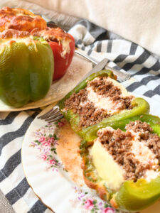 A plate with a stuffed pepper cut in half. There are more peppers on a plate in the background.