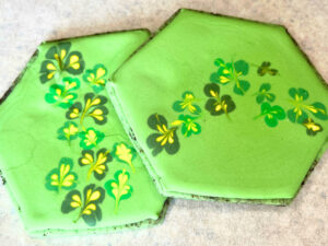 Two green decorated sugar cookies with a clover decoration.