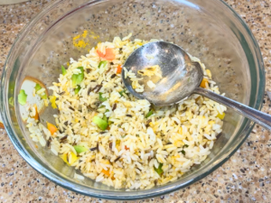 A mixed bowl of rice with diced veggies and spices in it.