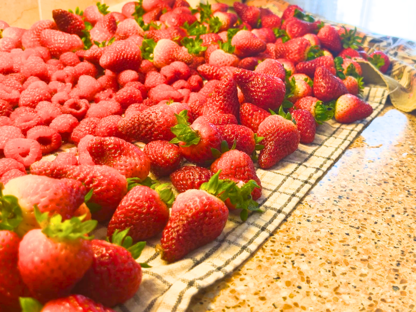 Strawberries and raspberries spread out on a kitchen towel.