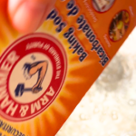 A woman pouring baking soda out of a box of arm and hammer baking soda.