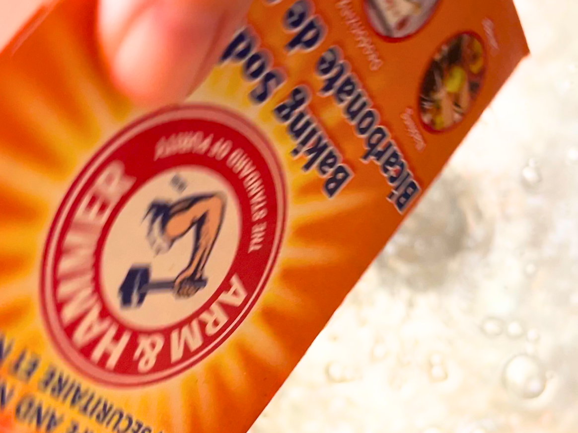 A woman pouring baking soda out of a box of arm and hammer baking soda.
