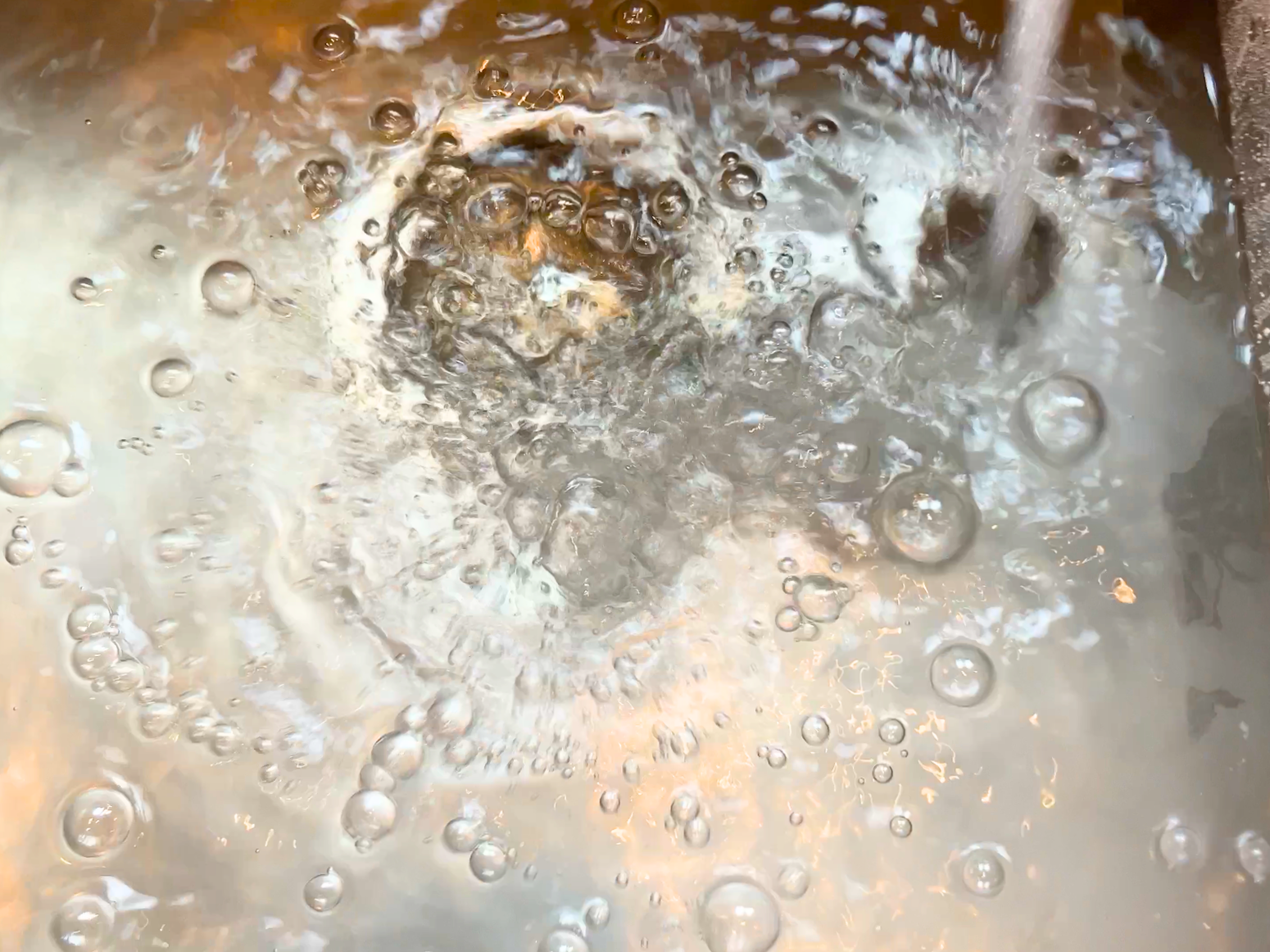 A sink filling up with running water.