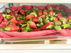 A casserole dish of strawberries in a refrigerator.