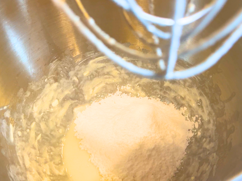 A mixing bowl with white liquid and powdered sugar inside.