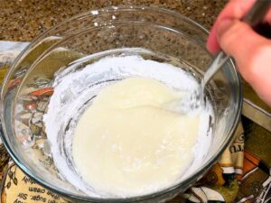 A woman mixing a sugar glaze.