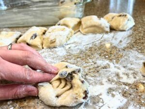 A woman folding a small section of dough.