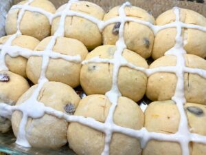 A plater of buns with a white cross of wet dough on each one.