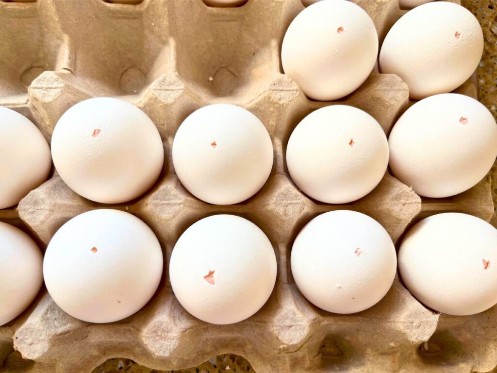 A collection of eggs with holes poked through the tops.