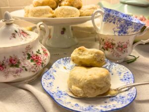 Some biscuits on a blue floral plate. There are more biscuits on a platter in the background. 