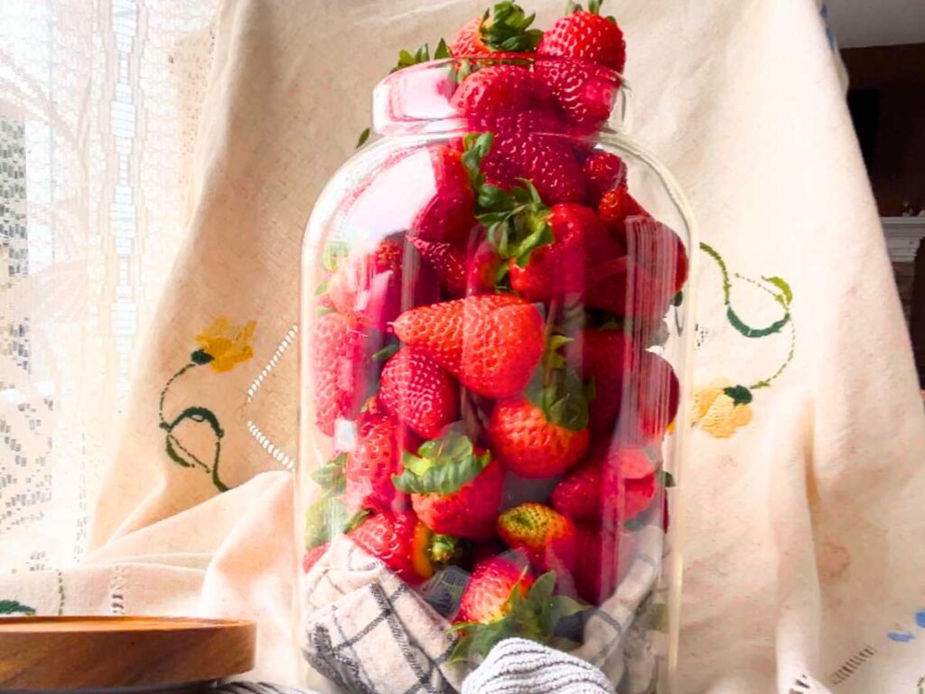 A glass jar filled with strawberries.