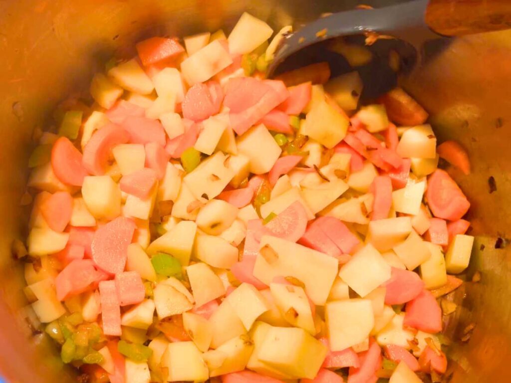 A mixture of chopped veggies in a large metal pot.