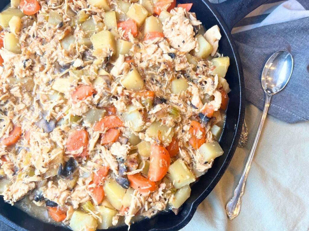 A cast iron skillet with a chicken and vegetable mixture inside.
